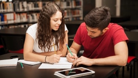 A boy and a girl study together at the library
