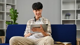 A boy studies on his tablet in his living room