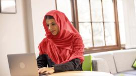 a woman with a headscarf sitting in front of an laptop